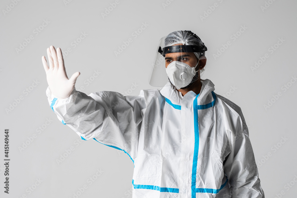 Medic man in a white hazmat suit and mask gesturing stop with hand isolated on white background Medic man in a white hazmat suit and mask gesturing stop with hand isolated on white background