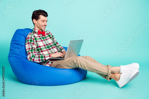 Profile photo of guy sit bag hold netbook toothy smile wear checkered shirt bow pants isolated blue color background