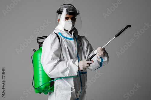 Full length profile shot of a medic man in a hazmat suit santizing with a spray on white background
