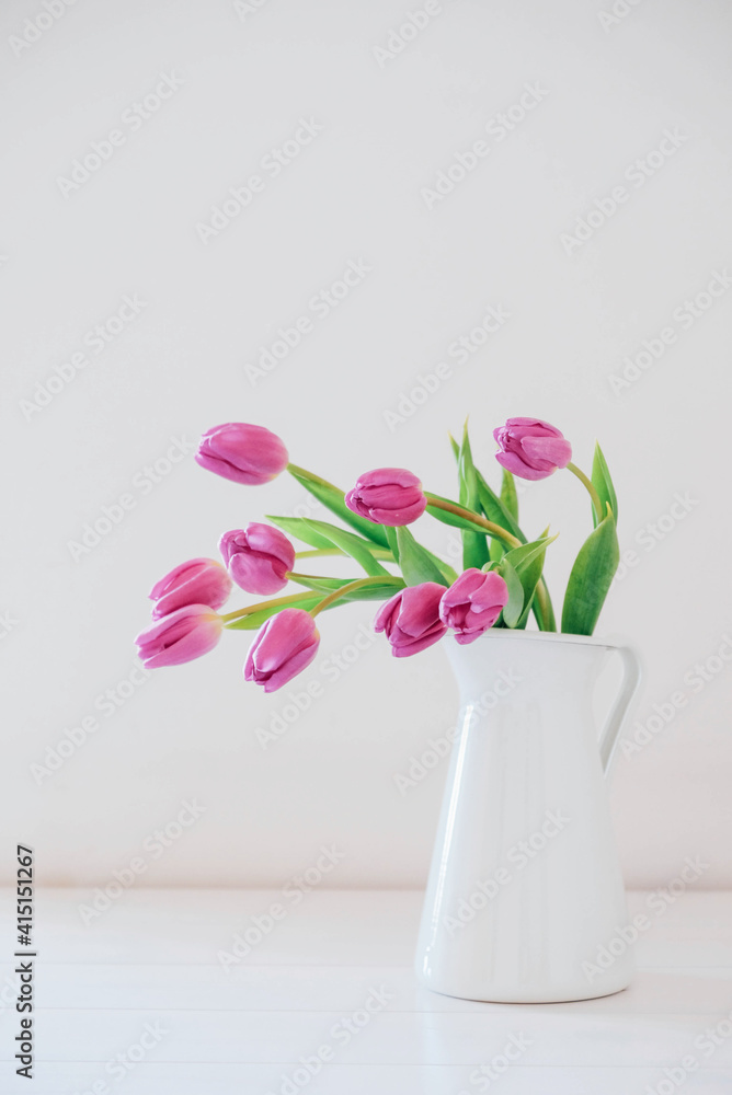 Beautiful mono bouquet of purple tulips in full bloom in white vase on white background. Copy space for text. Spring still life. Beautiful mono bouquet of purple tulips in full bloom in white vase on white background. Copy space for text. Spring still life.