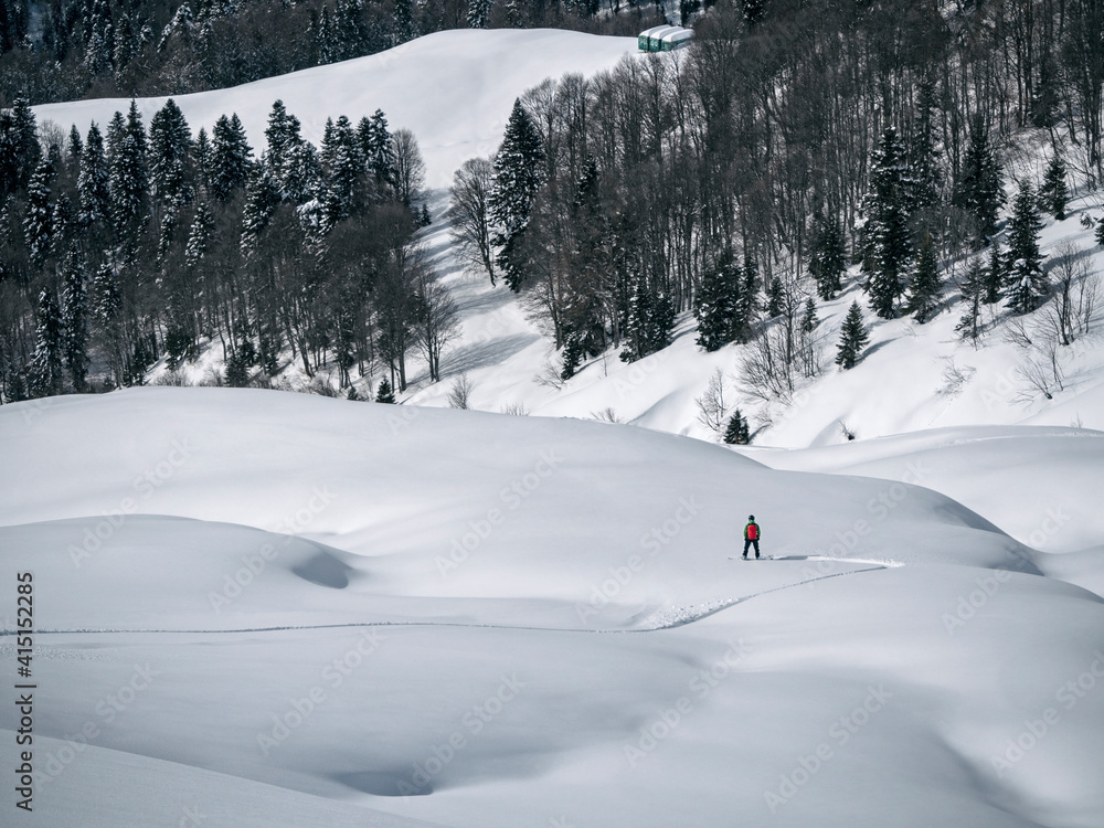 Man freeriding on snowboard and making first track on powder snow. Panoramic winter landscape