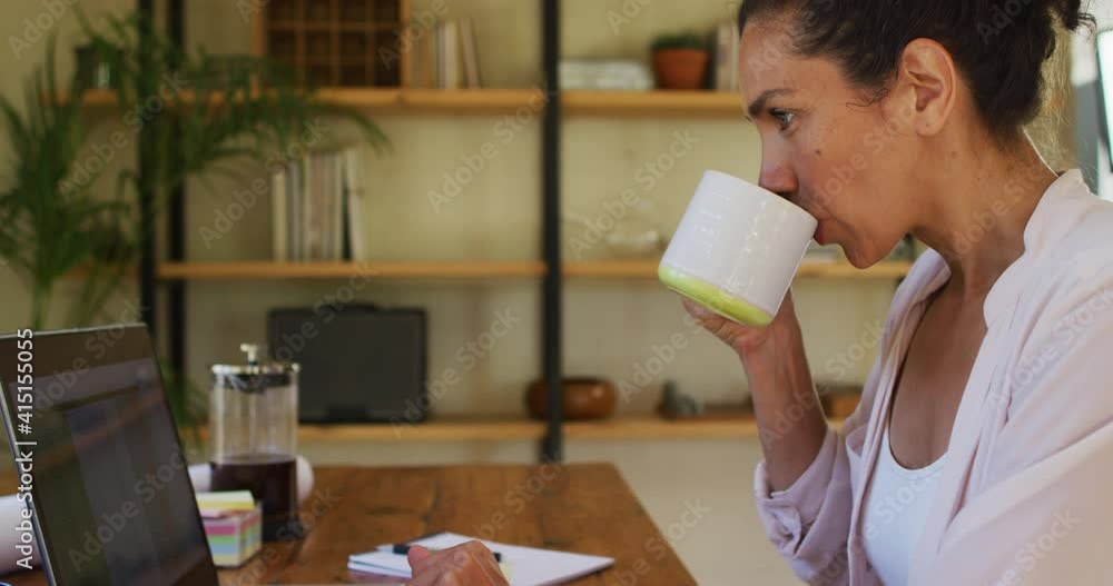 Mixed race woman drinking coffee and working from home Mixed race woman drinking coffee and working from home