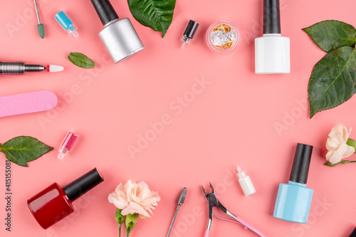 Colorful bottles of nail polishes and tools and accessories for manicure and pedicure procedures on a pink background. Top view and copy space
