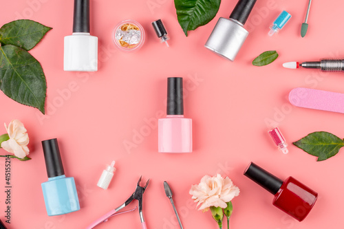 Colorful bottles of nail polishes and tools and accessories for manicure and pedicure procedures on a pink background. Top view