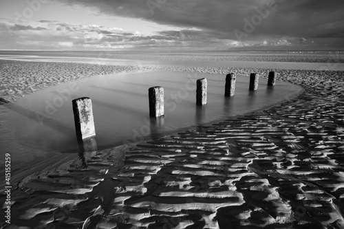 Rotting wooden posts of old sea defences on Winchelsea beach at low tide, Winchelsea, East Sussex photo