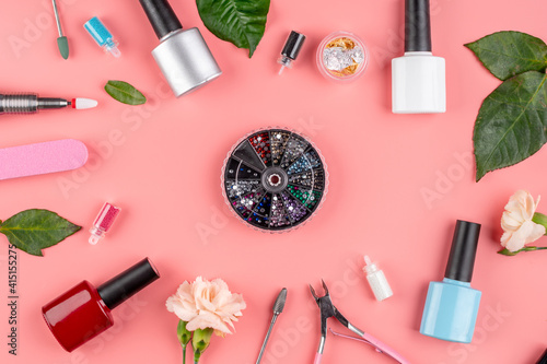 Colorful bottles of nail polishes and tools and accessories for manicure and pedicure procedures on a pink background. Top view