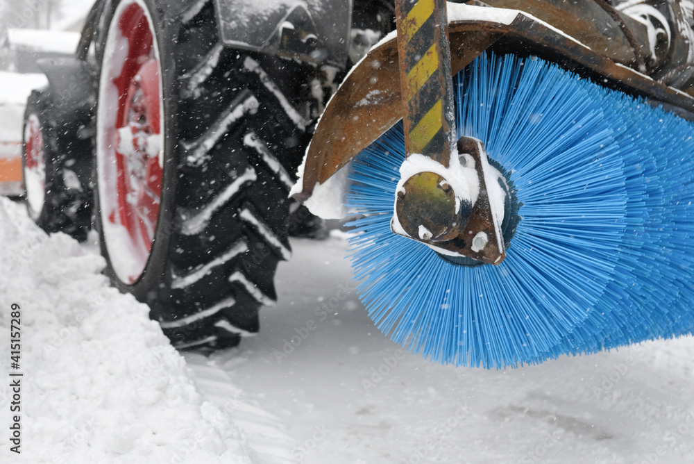 snow removal, urban. Tractor snowplow with a rotary brush and bucket removes snow from the city streets after the storm, clearing the passage for cars snow removal, urban. Tractor snowplow with a rotary brush and bucket removes snow from the city streets after the storm, clearing the passage for cars