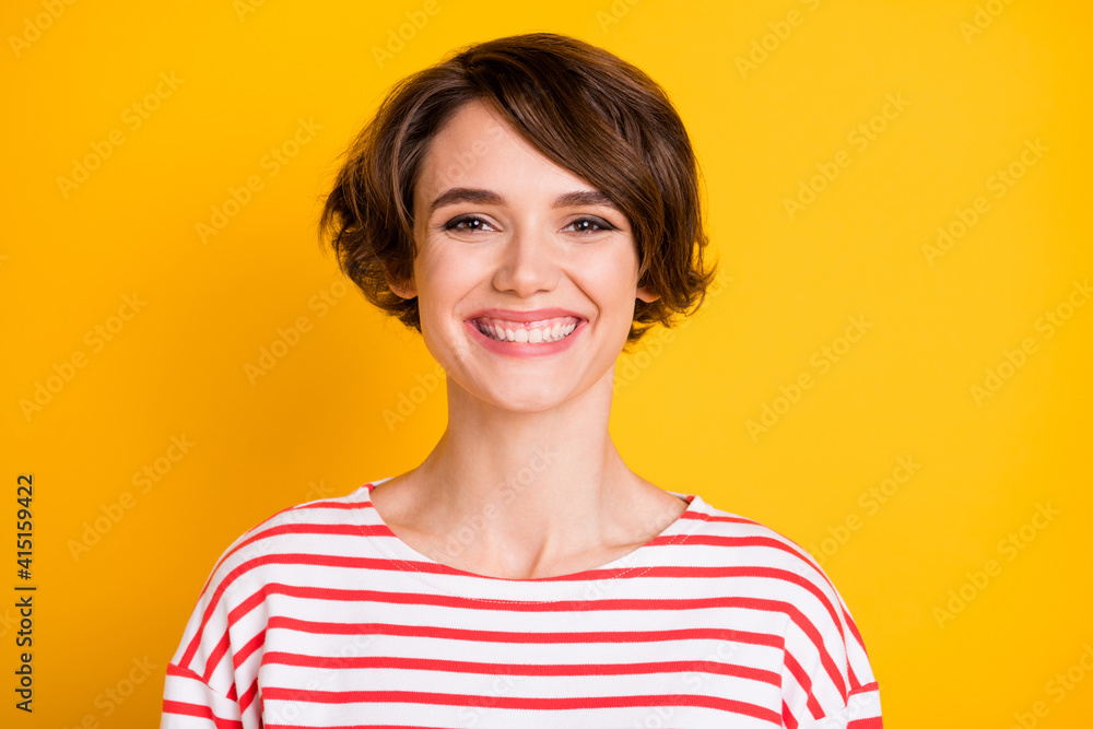 Portrait of young attractive lovely happy cheerful toothy girl smiling in striped jumper isolated on yellow color background Portrait of young attractive lovely happy cheerful toothy girl smiling in striped jumper isolated on yellow color background