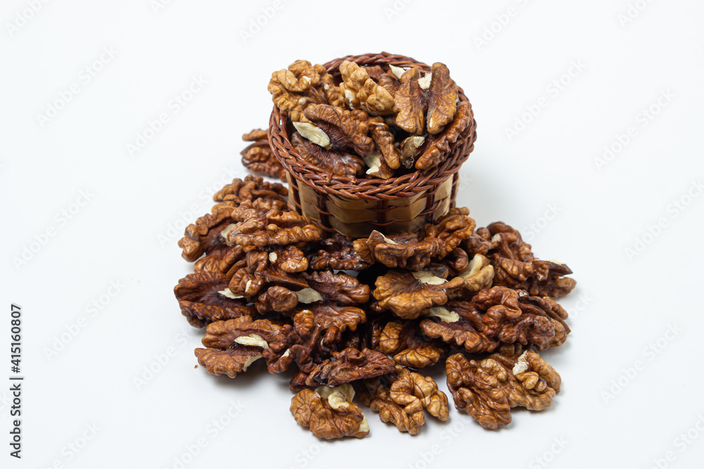 Peeled walnuts on a white background. A basket full of shelled walnuts. Nutritious food