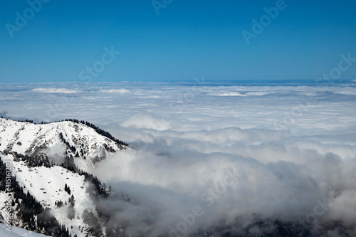 Mountain winter landscape. Higher than clouds. Mostly cloudy. Almaty region. Tien Shan mountains. Kazakhstan