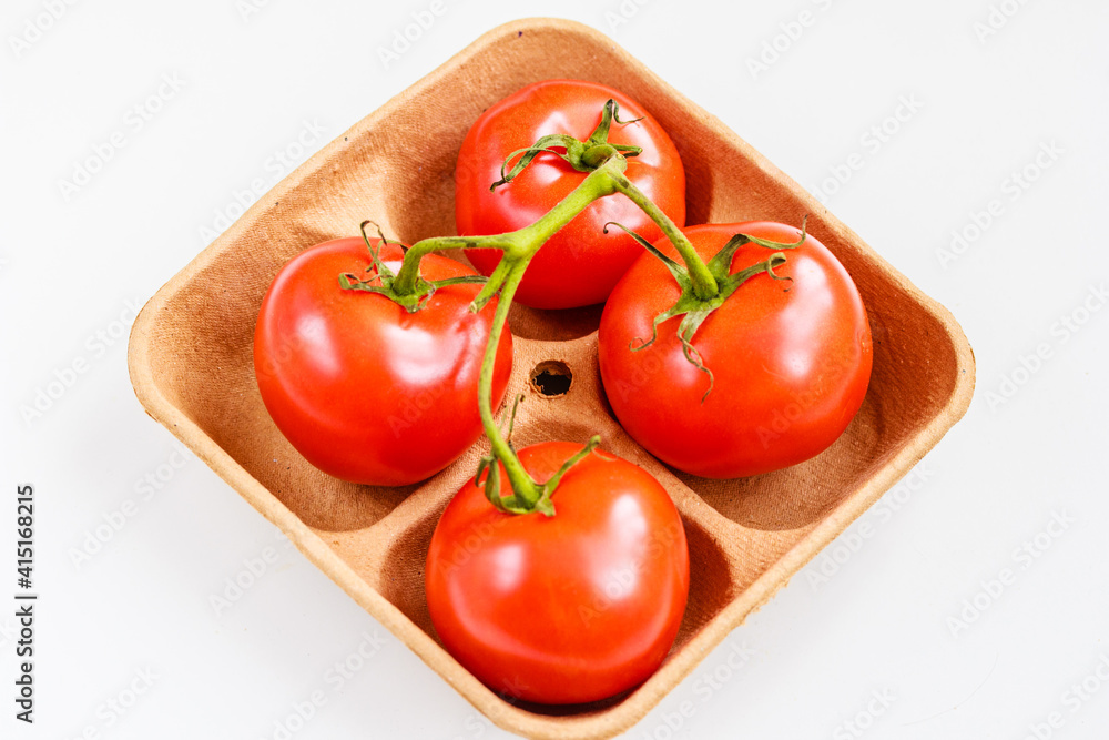 Fresh tomatoes on biodegradable pulp paper food tray isolated on white. Recyclable packaging concept. Top view, copy space Fresh tomatoes on biodegradable pulp paper food tray isolated on white. Recyclable packaging concept. Top view, copy space