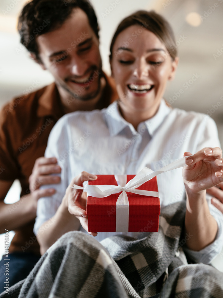 Husband surprising his wife with a gift. Young man giving a gift box to his wife. Husband surprising his wife with a gift. Young man giving a gift box to his wife.