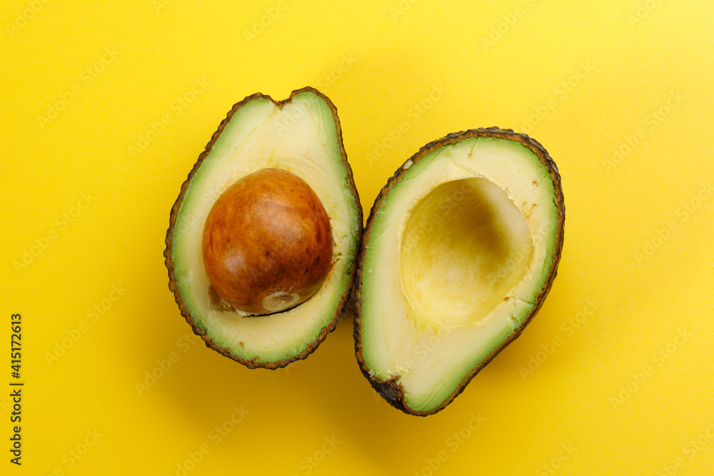 Avocado cut in half on a Yellow background