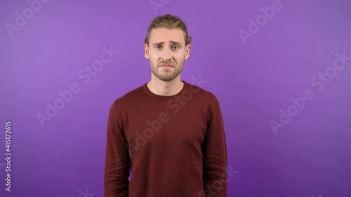 young long-haired guy showing dislik on isolated purple background 4k