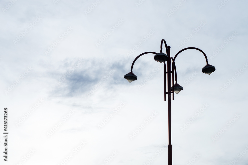 View of modern street light on cloudy sky background View of modern street light on cloudy sky background