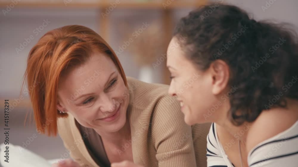 joyful interracial girlfriends talking and smiling at home joyful interracial girlfriends talking and smiling at home