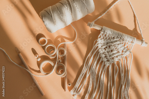 Macrame accessories on beige background. Creative hobby concept. Top view. Vintage color filter photo