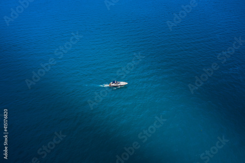 White yacht slow motion on blue water, boat top view. Boat in the sun. Lonely boat on blue water