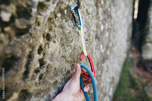 Close up of rock climber hand clipping rope in a quick draw caribener on a cliff face © olyphotostories