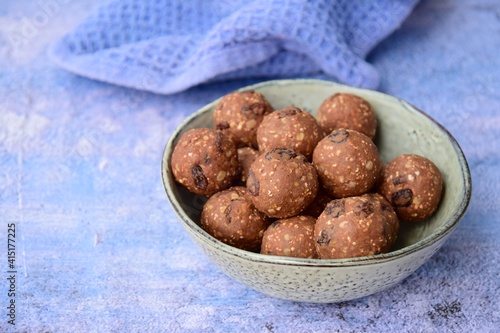Homemade healthy energy balls with chocolate, raisin, quinoa and oat on blue background
