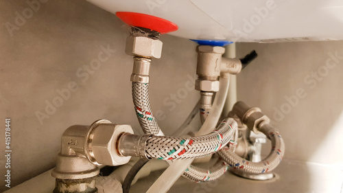 Connection of water supply, hot and cold water to the boiler. Hose for hot and cold water in the bathroom. Plumbing connections for a domestic electric water heater.