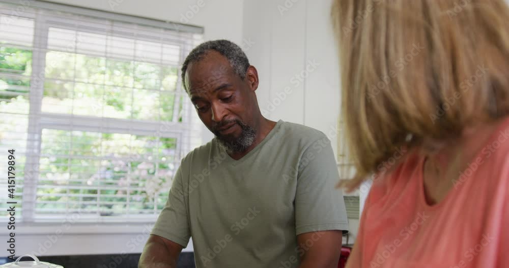 Happy diverse senior couple preparing food in kitchen and talking Happy diverse senior couple preparing food in kitchen and talking