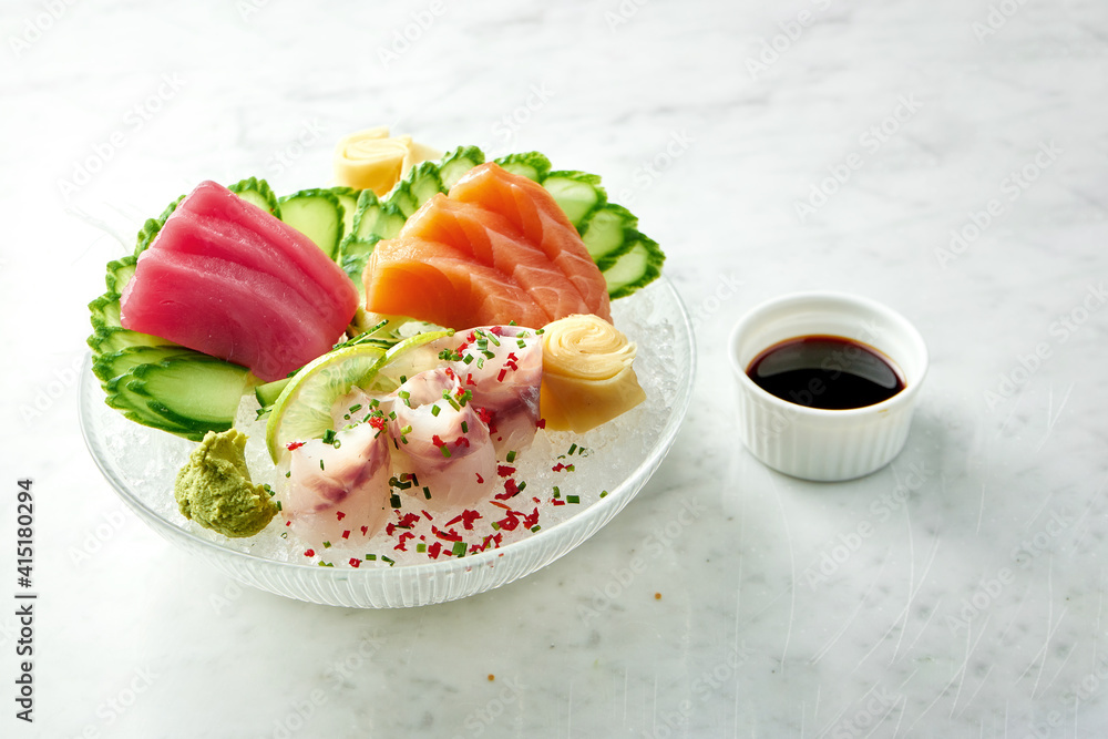 Classic Japanese sashimi set of raw salmon, eel and tuna with lime, cucumber on plate on a marble background. Close up, selective focus Classic Japanese sashimi set of raw salmon, eel and tuna with lime, cucumber on plate on a marble background. Close up, selective focus