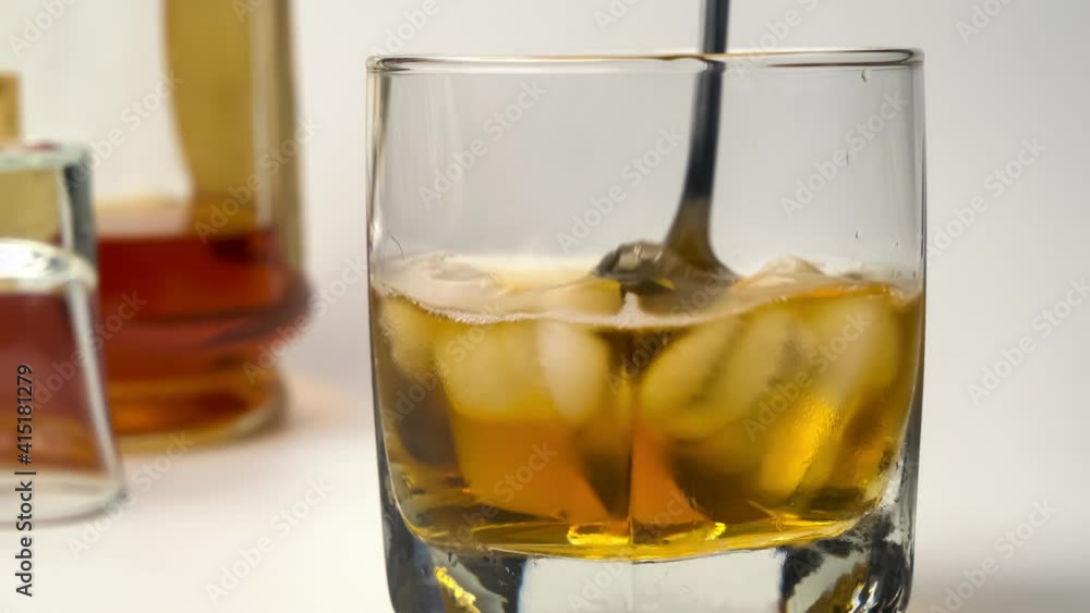 Closeup of using metal spoon stir up whiskey and ice in a glass on white background. Closeup of using metal spoon stir up whiskey and ice in a glass on white background.