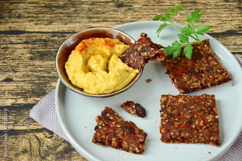 Homemade seed crackers made from bell pepper, sun dried tomato, sunflower seed, sesame seed, hemp seed and flax seeds. Served with hummus dip