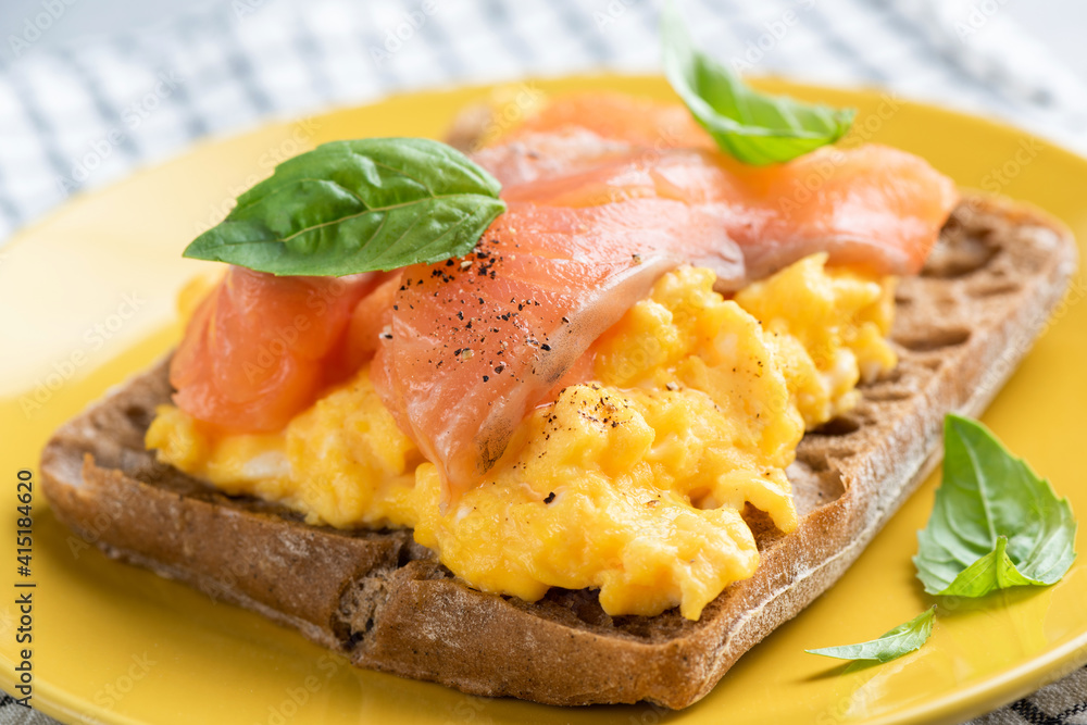 Breakfast or lunch sandwich with scrambled eggs and salmon. Closeup view