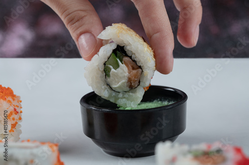 Dipping sushi roll into wasabi sauce and ginder  photo