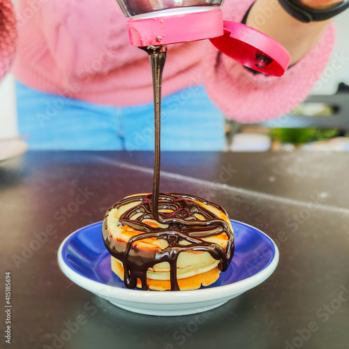 Glassa al cioccolato mentre viene versata su dei pancake appena cotti photo