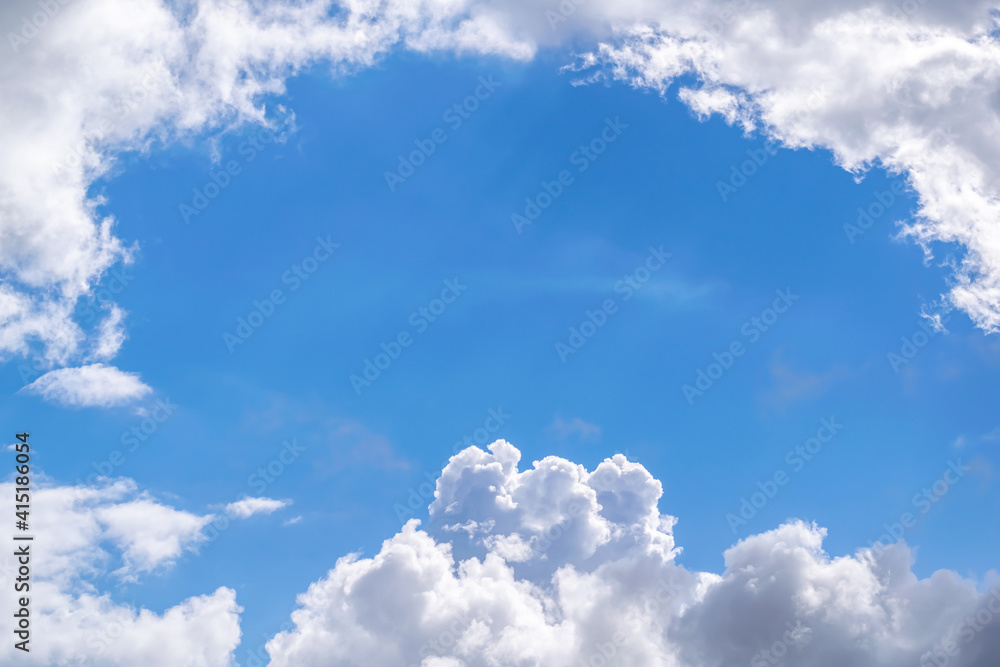 A patch of blue sky surrounded by clouds on a clear sunny day.
