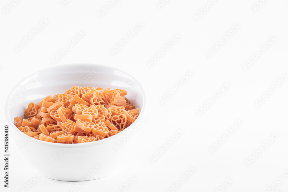 Bowl of raw heart shaped pasta on white background Bowl of raw heart shaped pasta on white background