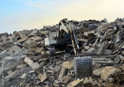 Recycling concrete and construction waste from demolition. Excavator at landfill of the disposa. Reuse of building rubble. Backhoe dig gravel at mining quarry on sunset background. Concrete debris