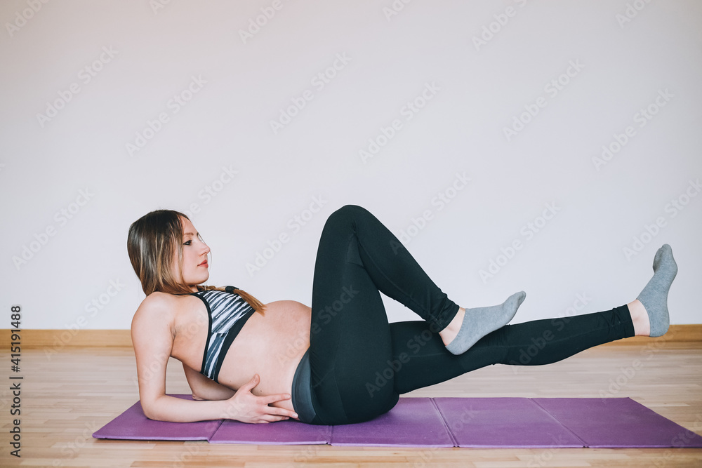Young beautiful caucasian pregnant woman training at home