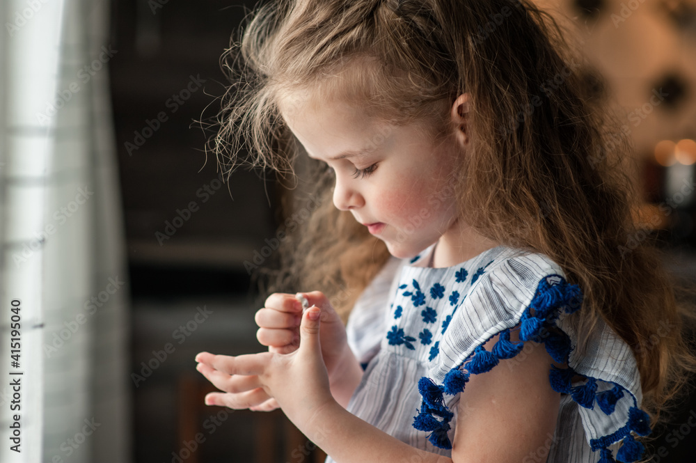 A cute little girl with long curly hair holds Easter eggs in her hands. Portrait. Close-up A cute little girl with long curly hair holds Easter eggs in her hands. Portrait. Close-up