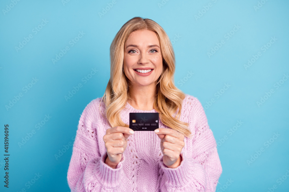 Photo portrait of blonde woman smiling showing bank credit card isolated vibrant blue color background Photo portrait of blonde woman smiling showing bank credit card isolated vibrant blue color background