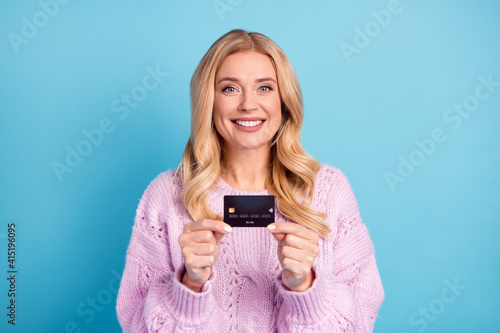 Photo portrait of blonde woman smiling showing bank credit card isolated vibrant blue color background