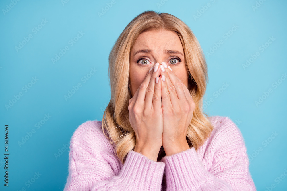 Photo portrait of blonde woman terrified stressed covered face with hands fear staring isolated vibrant blue color background Photo portrait of blonde woman terrified stressed covered face with hands fear staring isolated vibrant blue color background