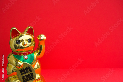 Maneki-neko. Japanese Chinese cat of fortune and luck on a red background with copy space