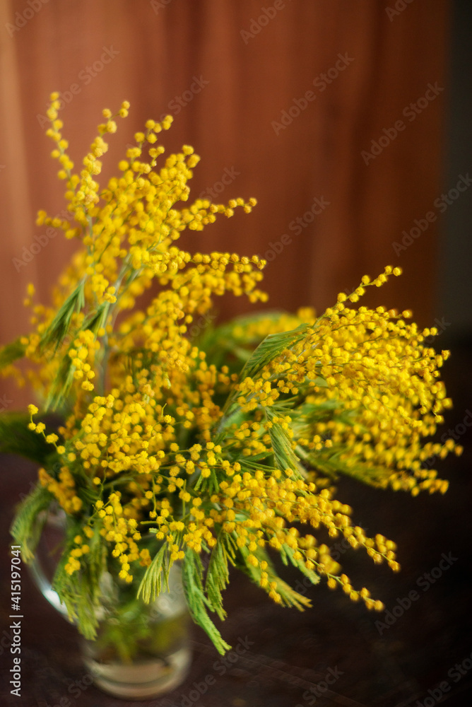 Obraz premium Bouquet of yellow mimosa in a vase on a wooden background