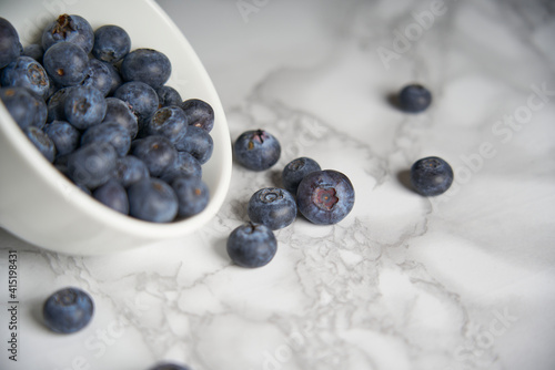 A group of fresh blueberries on a white and black marble table. 