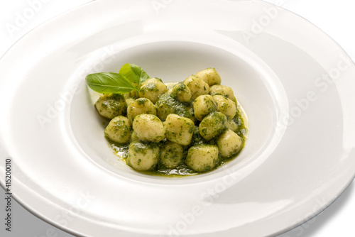 Gnocchi al pesto from Genoa, traditional Italian recipe made of fresh basil, olive oil, pine nuts. In white dish isolated on white