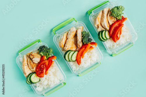 top view of vegetables, rice, meat in plastic bowls on light green background photo