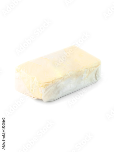 piece of butter made from cow's milk wrapped in transparent paper  side view on white background isolated with clipping path closeup. Selective focus.