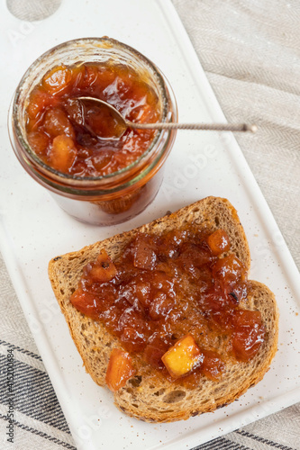 Homemade apple jam marmalade with cloves and cinnamon from organic apples  in glass jar and  wholemeal bread near vintage teaspoon. Homemade autumn jam preserves. Apple jam sandwich  toast breakfast 