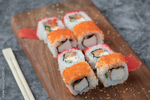 Sushi rolls with yellow and red caviar on a wooden board