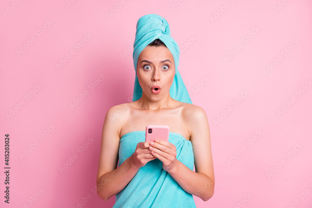 Photo of young beautiful shocked amazed surprised girl wear turquoise turban towel hold phone isolated on pink color background Photo of young beautiful shocked amazed surprised girl wear turquoise turban towel hold phone isolated on pink color background