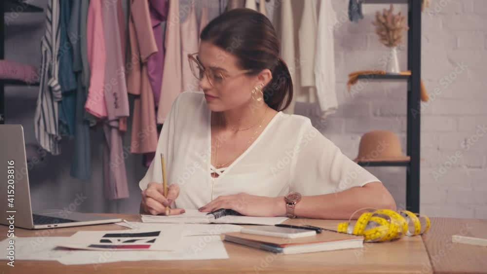 Designer using laptop and writing on notebook Designer using laptop and writing on notebook